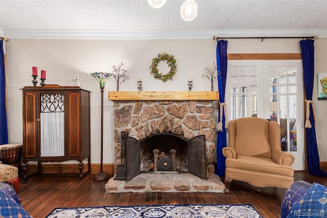 living area with crown molding, baseboards, a fireplace, an ornate ceiling, and wood-type flooring