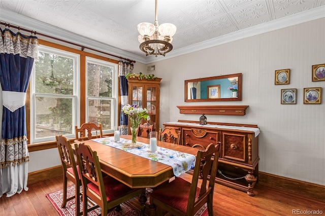 dining room with hardwood / wood-style floors, baseboards, an ornate ceiling, ornamental molding, and a chandelier