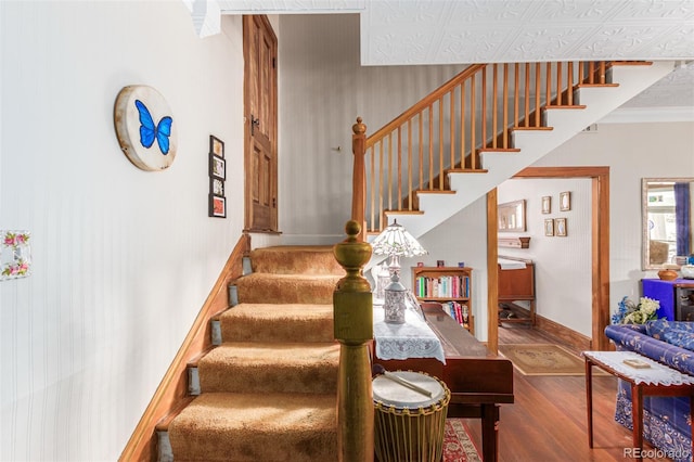 staircase with baseboards, wood finished floors, and ornamental molding