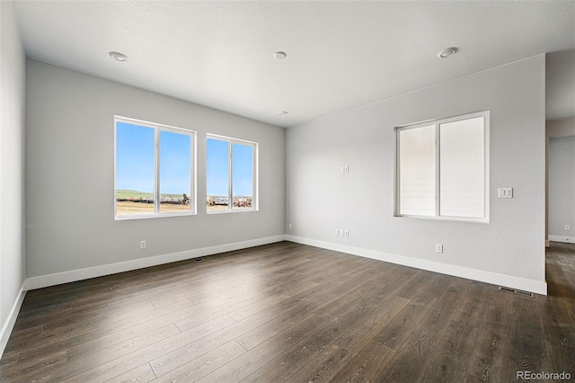 unfurnished room with dark wood-type flooring and baseboards