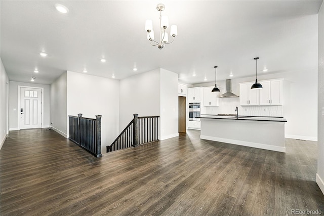 unfurnished living room with recessed lighting, dark wood-type flooring, baseboards, a chandelier, and a sink