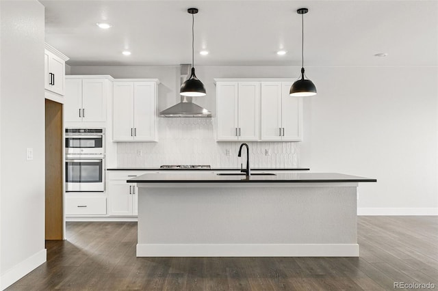 kitchen featuring a sink, dark countertops, appliances with stainless steel finishes, wall chimney exhaust hood, and tasteful backsplash