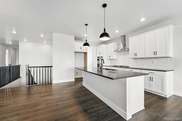 kitchen with wall chimney range hood, dark countertops, a sink, stainless steel appliances, and dark wood-style floors