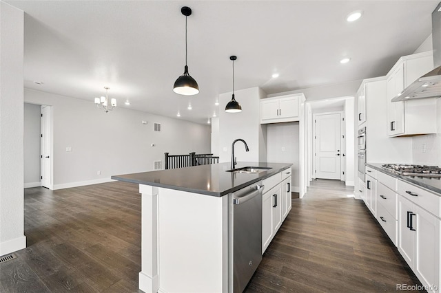 kitchen featuring a sink, appliances with stainless steel finishes, dark countertops, wall chimney exhaust hood, and baseboards