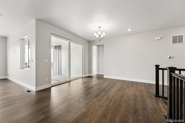 empty room with a chandelier, dark wood finished floors, baseboards, and recessed lighting