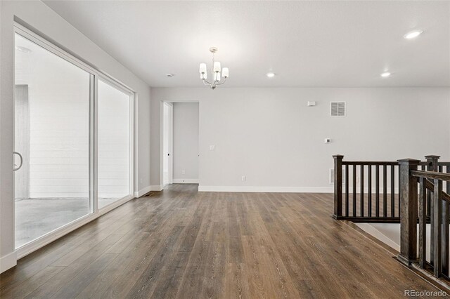 spare room with a chandelier, dark wood-style flooring, recessed lighting, and baseboards
