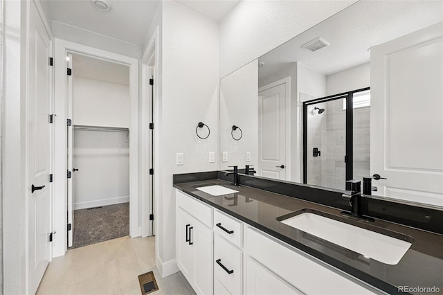 full bathroom featuring a stall shower, a walk in closet, double vanity, and baseboards