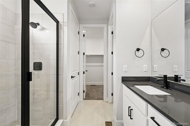 bathroom featuring a shower stall, vanity, and a walk in closet