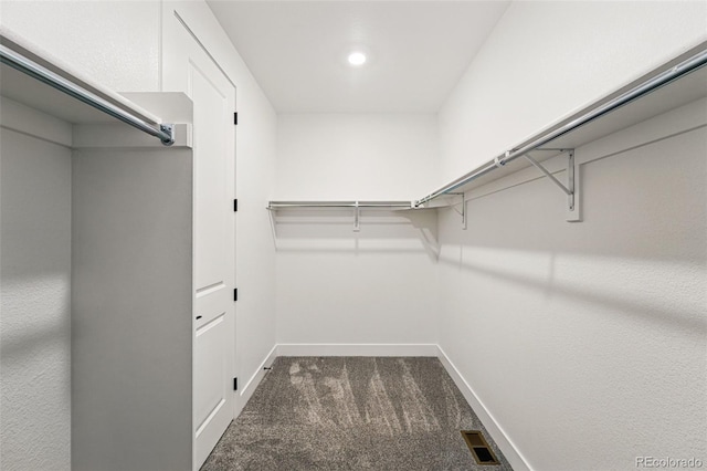 walk in closet with dark carpet