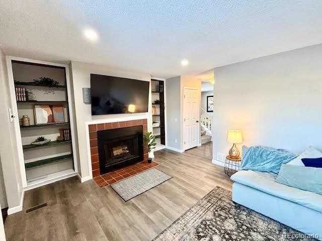 living room featuring hardwood / wood-style flooring, a fireplace, and a textured ceiling