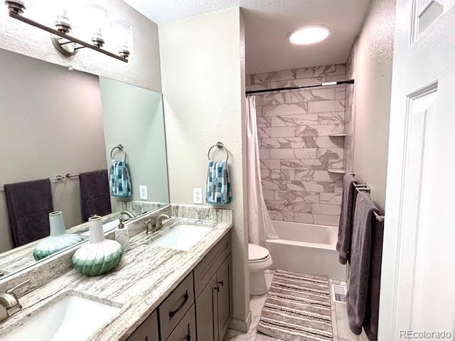 full bathroom with vanity, shower / tub combo, and toilet