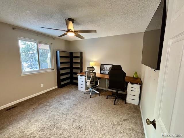 carpeted home office with a textured ceiling and ceiling fan