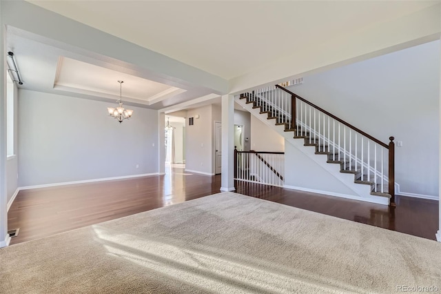 interior space with dark hardwood / wood-style flooring, a raised ceiling, and an inviting chandelier