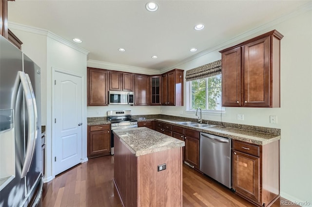 kitchen with a center island, sink, ornamental molding, appliances with stainless steel finishes, and light stone counters