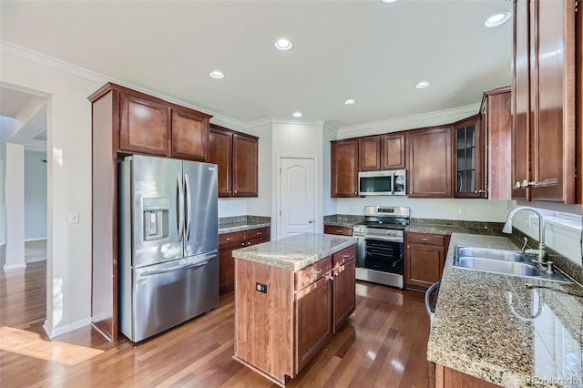 kitchen with stone counters, a center island, stainless steel appliances, and sink