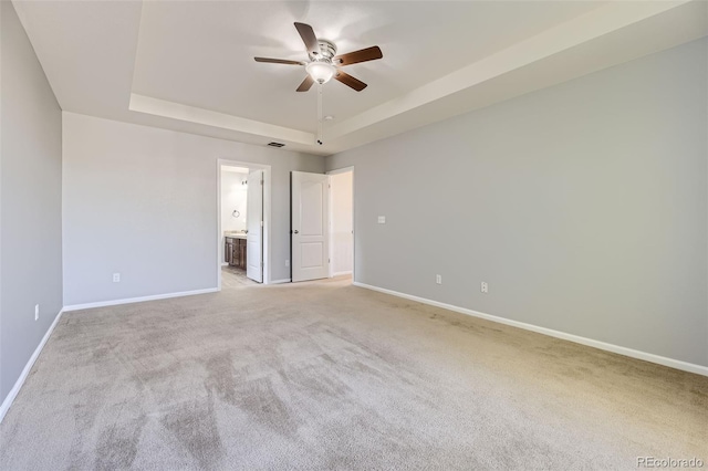 carpeted spare room featuring a raised ceiling and ceiling fan