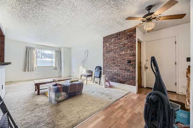 living room featuring light hardwood / wood-style floors, ceiling fan, and a textured ceiling