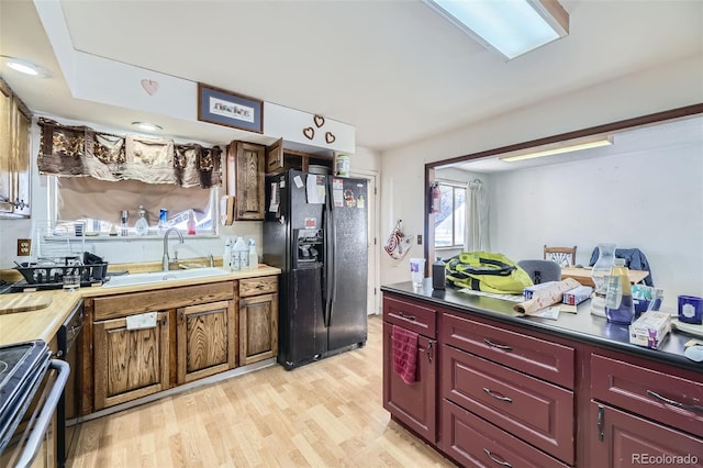 kitchen featuring black fridge, sink, stainless steel range with electric cooktop, and light hardwood / wood-style flooring