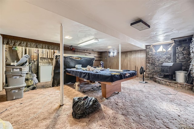 playroom featuring pool table, washer / clothes dryer, wooden walls, and a wood stove