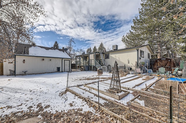 snow covered rear of property with a storage unit and cooling unit