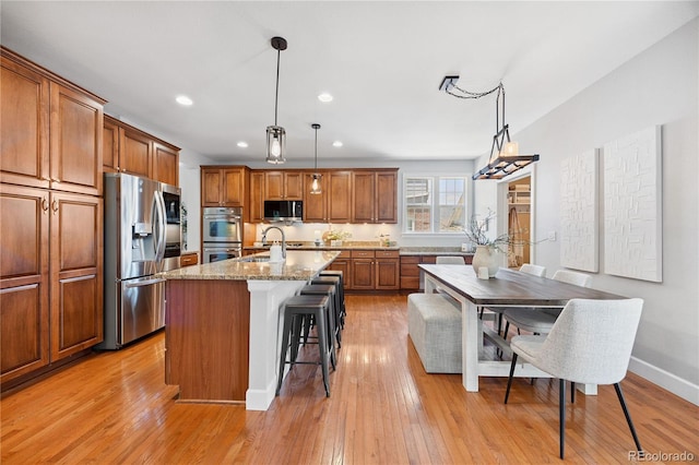 11674 Newton St, Westminster, CO 80031 - kitchen featuring stainless steel appliances, brown cabinets, a breakfast bar area, recessed lighting, and light stone countertops