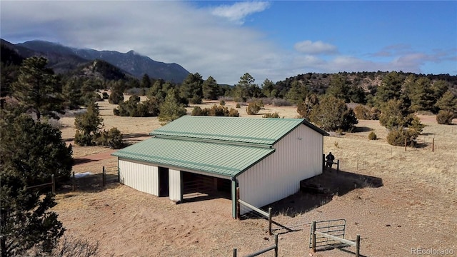 view of side of home with a rural view, a mountain view, an exterior structure, and an outbuilding