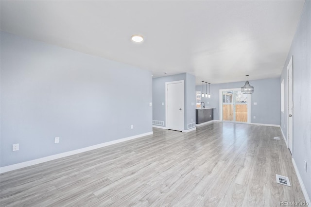 unfurnished living room with a chandelier, sink, and light wood-type flooring