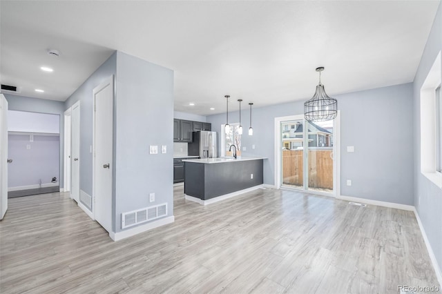 kitchen featuring stainless steel refrigerator with ice dispenser, sink, pendant lighting, and light hardwood / wood-style floors