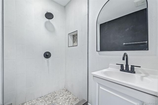 bathroom with a tile shower and vanity