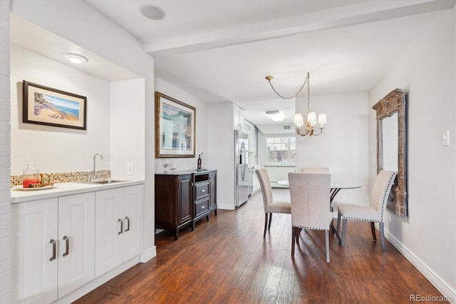 dining space with dark wood-type flooring, indoor wet bar, and an inviting chandelier