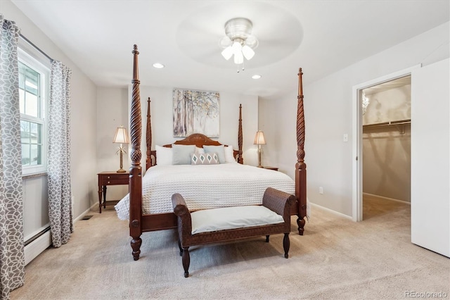 carpeted bedroom with a baseboard radiator, a walk in closet, ceiling fan, and a closet