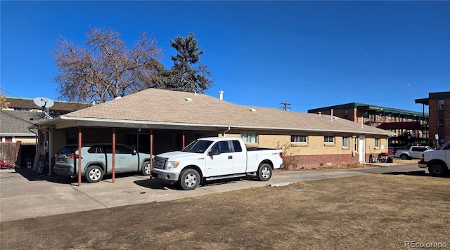 view of front of house with a carport, concrete driveway, brick siding, and roof with shingles