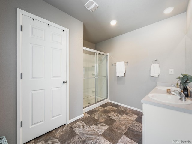 bathroom featuring a shower with shower door and vanity