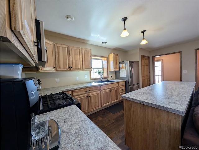 kitchen featuring plenty of natural light, pendant lighting, gas stove, and stainless steel fridge