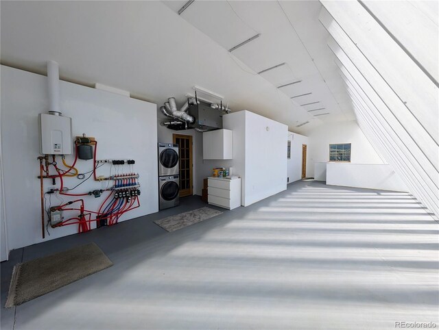 garage featuring tankless water heater and stacked washer / drying machine