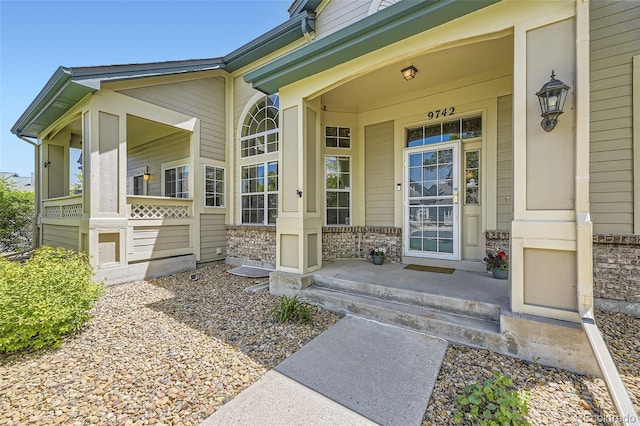 doorway to property with covered porch and brick siding