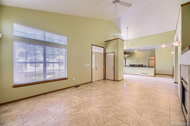unfurnished living room featuring ceiling fan, light tile patterned floors, a fireplace, baseboards, and high vaulted ceiling