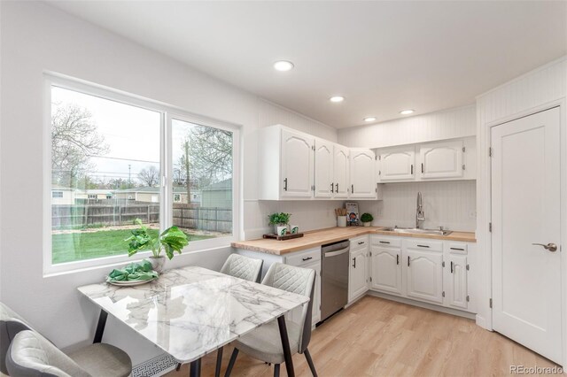 kitchen featuring stainless steel dishwasher, a sink, white cabinetry, light wood finished floors, and recessed lighting