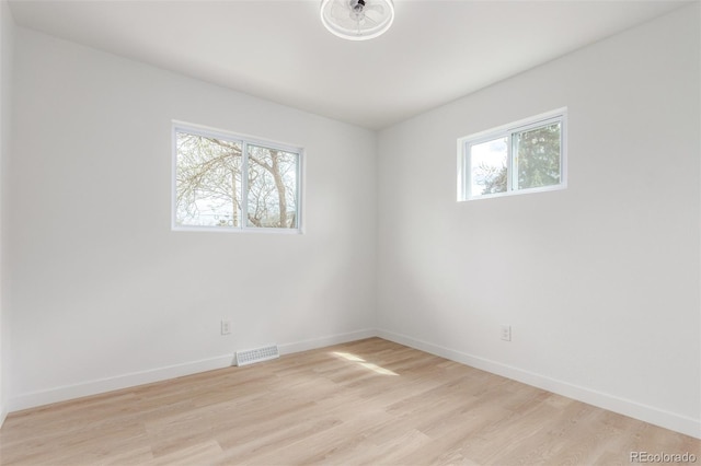 unfurnished room featuring plenty of natural light, light wood finished floors, and baseboards