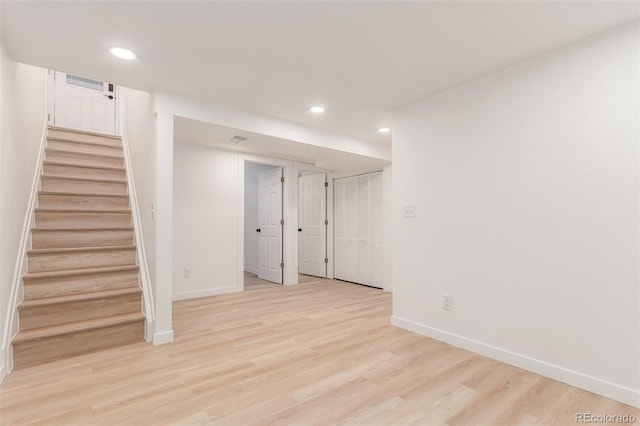 finished basement featuring recessed lighting, baseboards, stairs, and light wood-type flooring