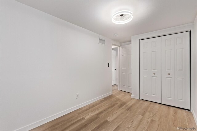 unfurnished bedroom with light wood-type flooring, baseboards, and a closet