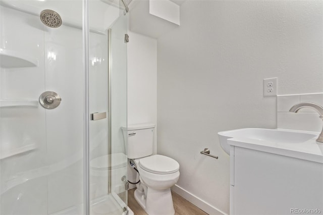 full bath featuring a shower stall, wood finished floors, toilet, vanity, and baseboards