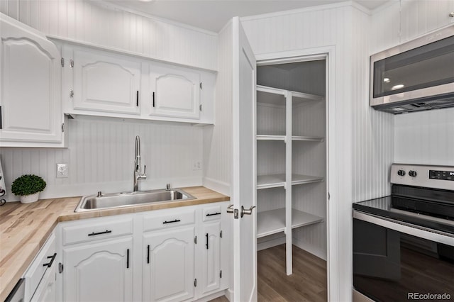 9120 Judson St, Westminster, CO 80031 - kitchen with stainless steel appliances, a sink, white cabinetry, butcher block counters, and wood finished floors