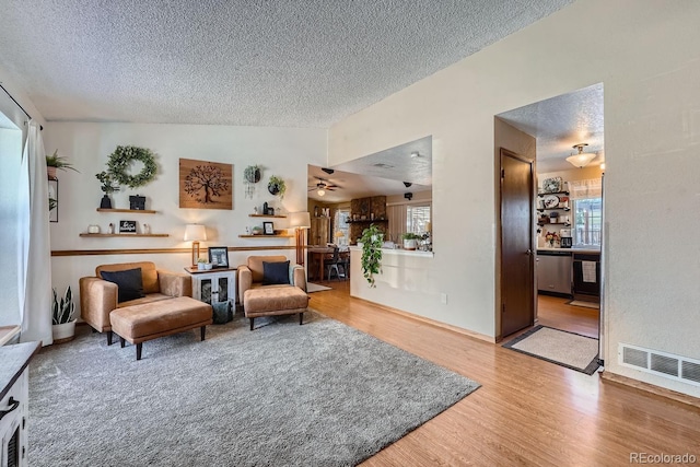 sitting room featuring wood-type flooring, vaulted ceiling, a textured ceiling, and ceiling fan