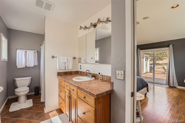 bathroom with vanity, toilet, baseboards, and visible vents