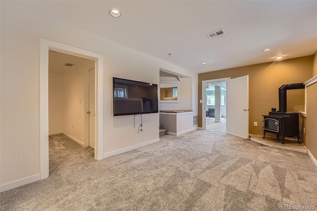 unfurnished living room with recessed lighting, a wood stove, baseboards, and carpet floors