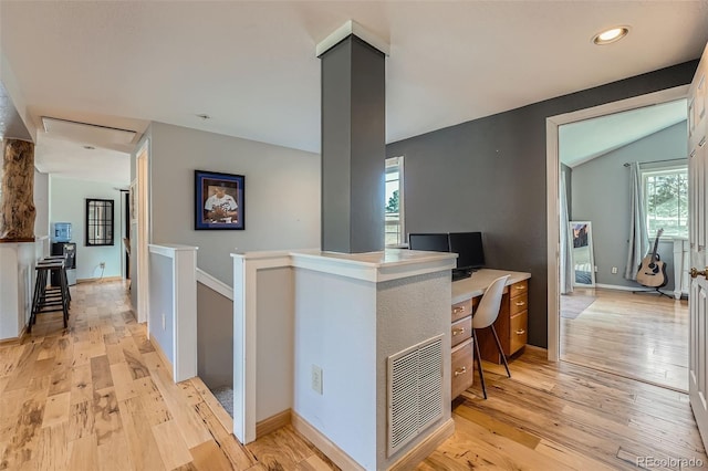 hall featuring visible vents, light wood finished floors, baseboards, lofted ceiling, and an upstairs landing