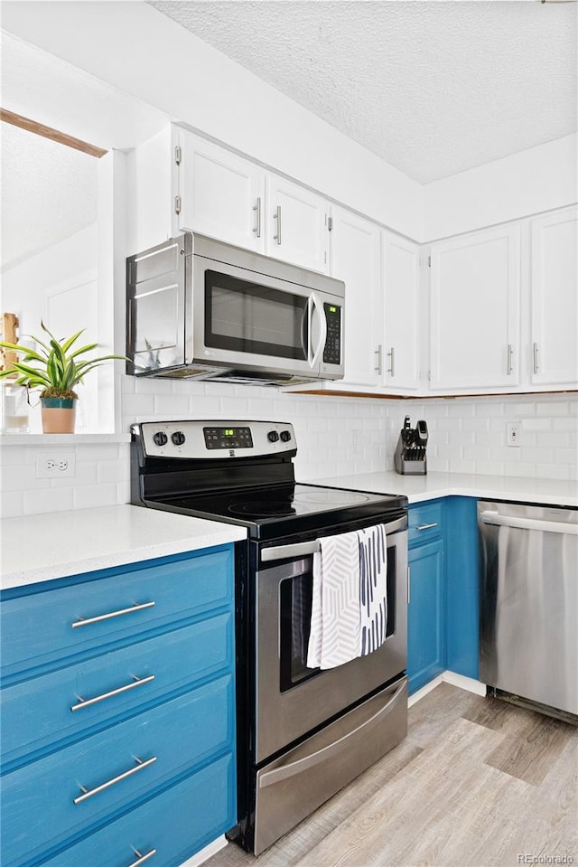 209 Wright St Unit 204, Lakewood, CO 80228 - kitchen featuring light wood-type flooring, light countertops, appliances with stainless steel finishes, blue cabinets, and tasteful backsplash
