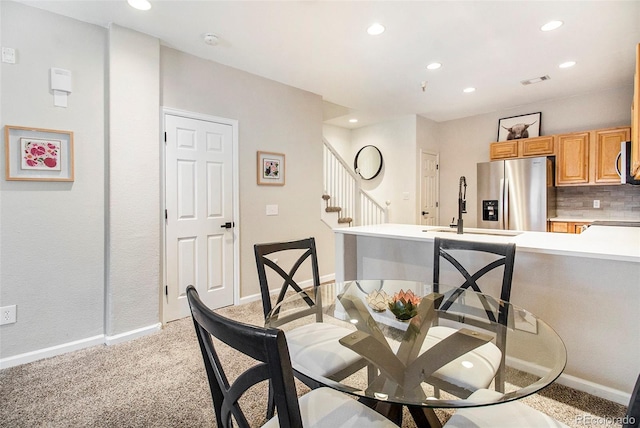 dining area featuring sink and light colored carpet