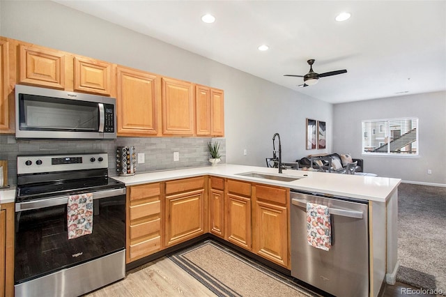 kitchen featuring sink, ceiling fan, appliances with stainless steel finishes, tasteful backsplash, and kitchen peninsula